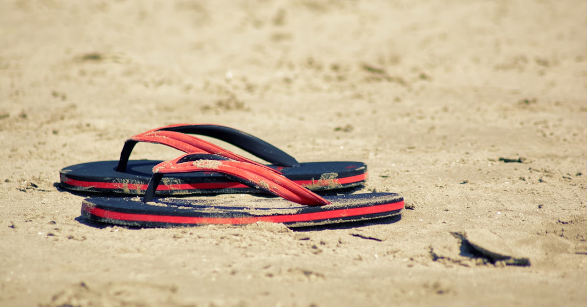 Par de chinelos de praia sobre areia, representando o estilo despretensioso que fez das Havaianas um símbolo nacional