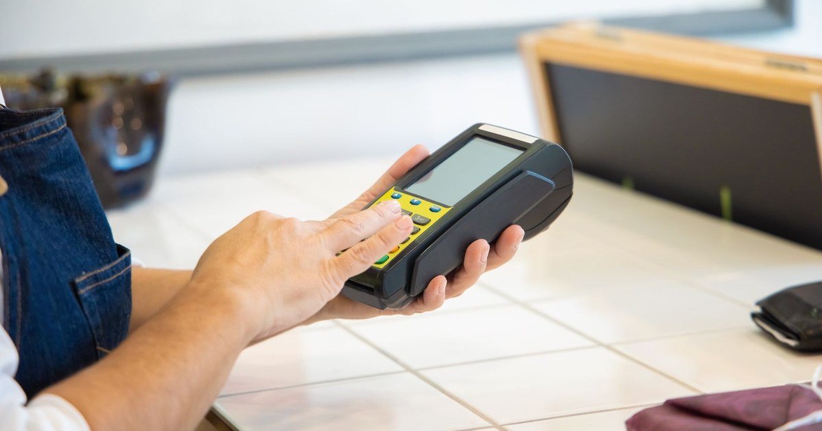 Pessoa digitando a senha numa maquininha de cartão, ilustrando o pagamento parcelado nas compras de Black Friday