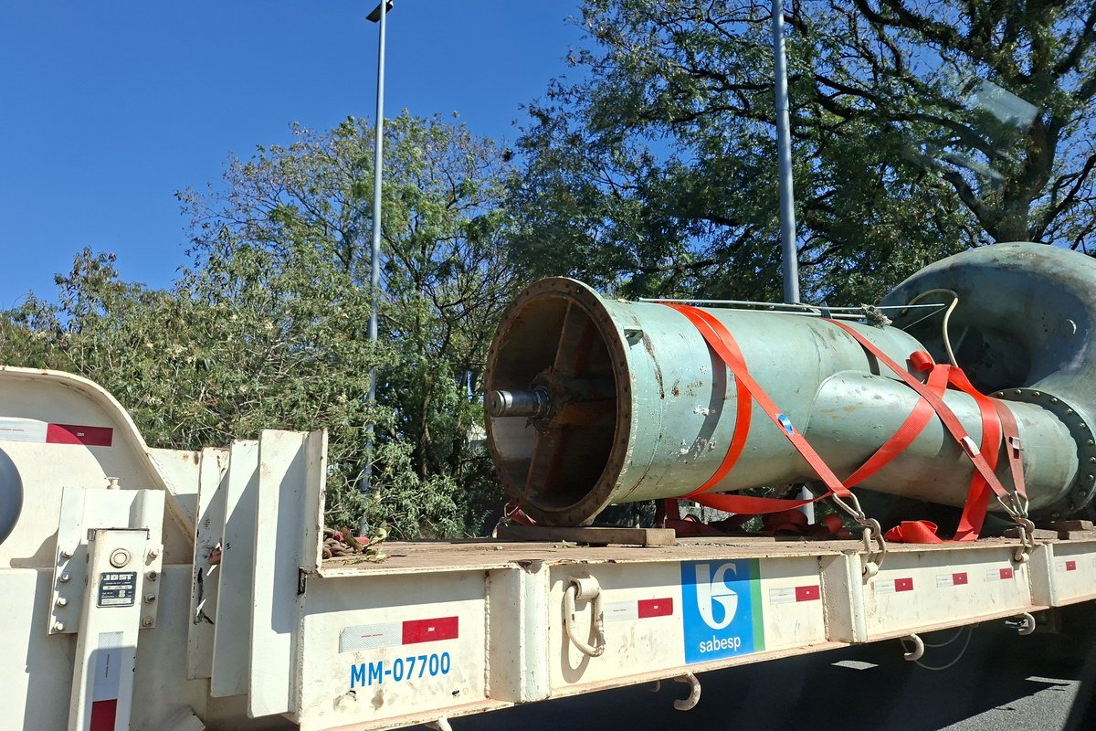 Grande tubulação metálica de saneamento da Sabesp transportada em caminhão, com o logotipo da empresa visível