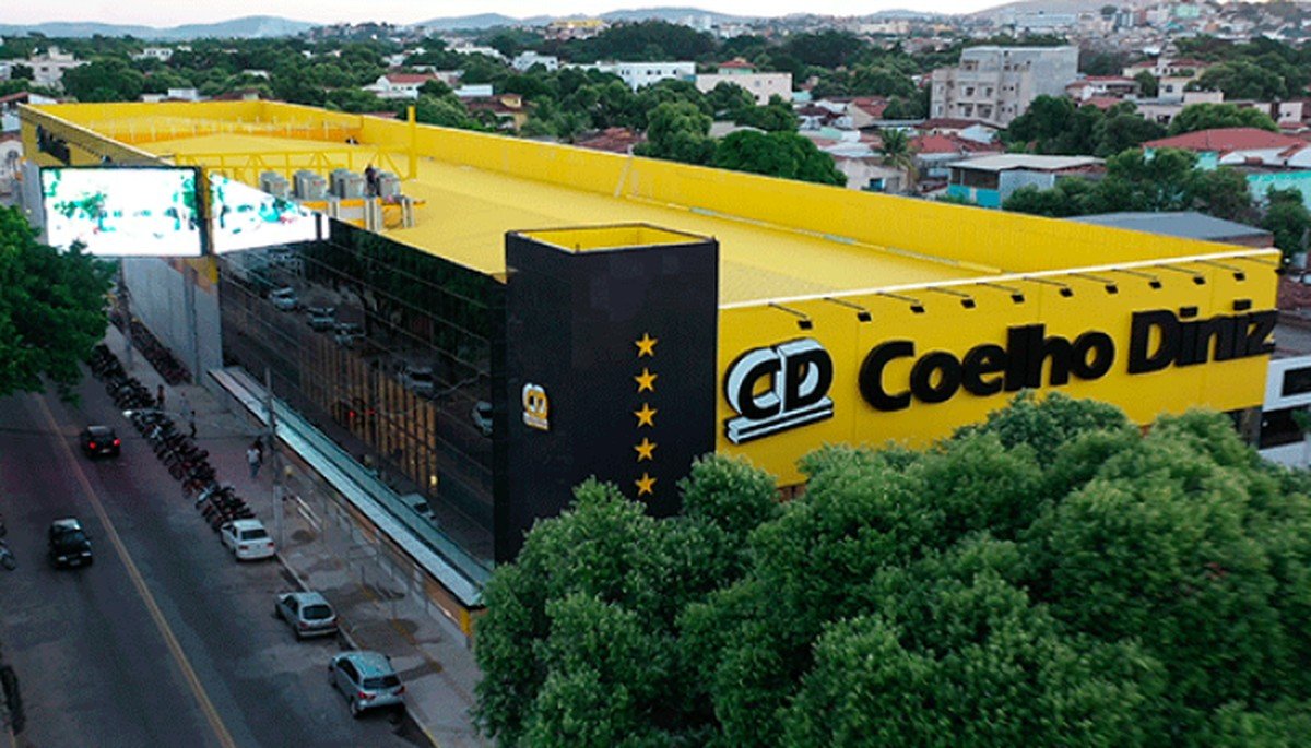 Loja da rede Coelho Diniz Supermercados, em Governador Valadares (MG) — a família que hoje é a maior acionista do GPA, sem parentesco com os fundadores Vista aérea de uma loja da rede Coelho Diniz, com fachada preta e amarela, painel de LED e estacionamento, cercada por vegetação e construções de Governador Valadares