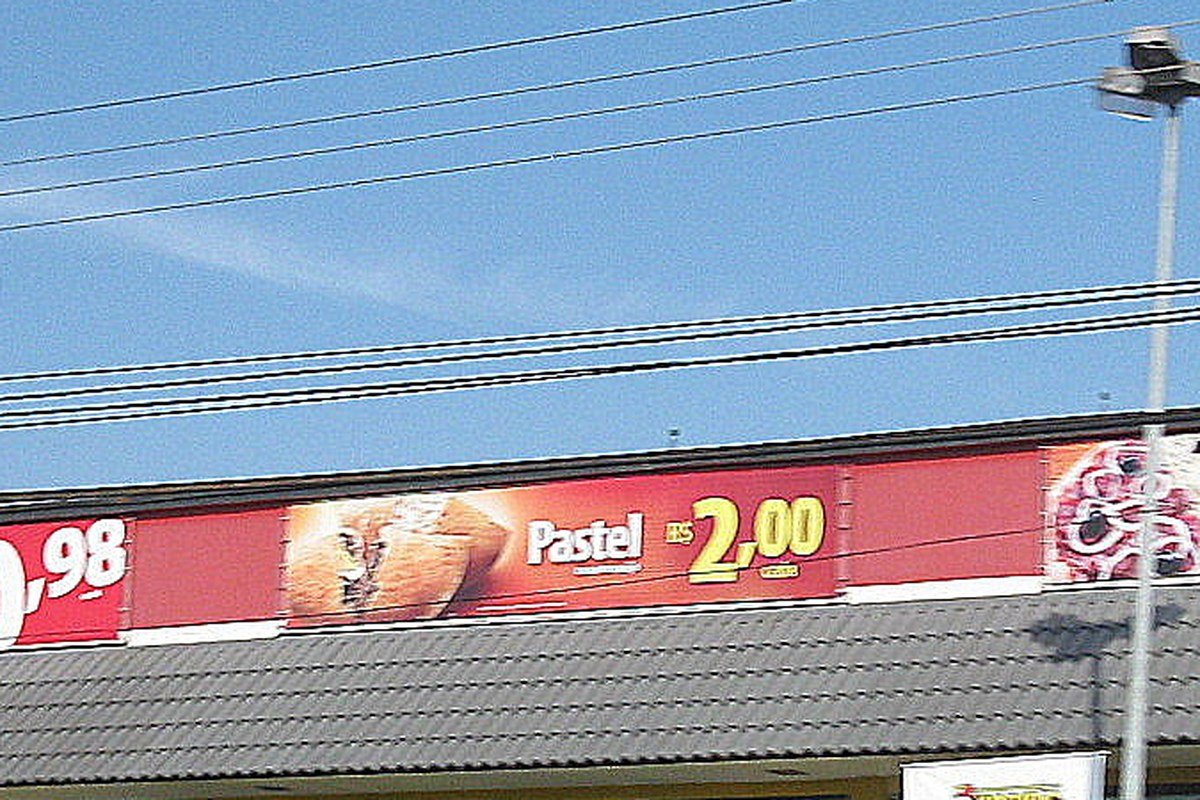 Faixa de preços populares (pastel a R$ 2,00, pizza a R$ 13,90) em loja do Habib's, ilustrando a estratégia histórica de preços baixos da rede