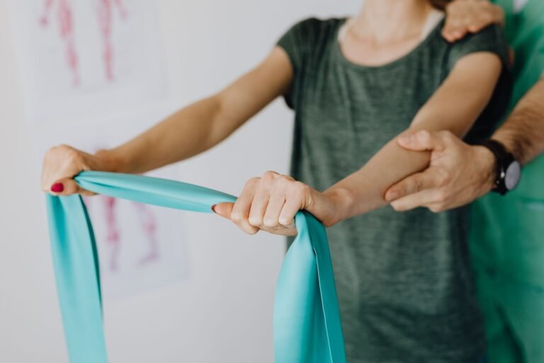 Profissional acompanha exercício com faixa elástica; foto ilustrativa de reabilitação