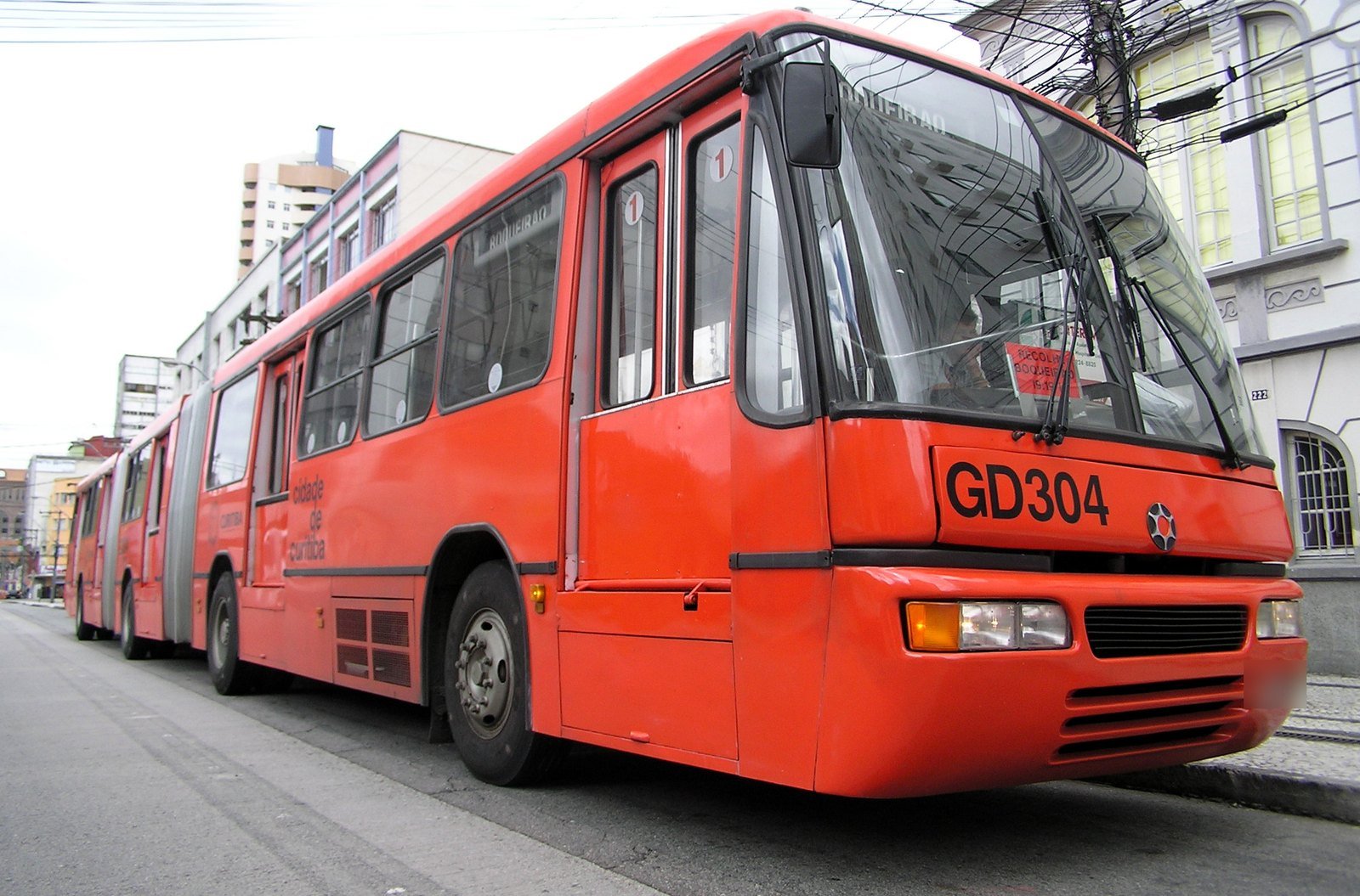 Ônibus biarticulado vermelho do Expresso de Curitiba, com chassi Volvo B58, estacionado em uma rua da cidade