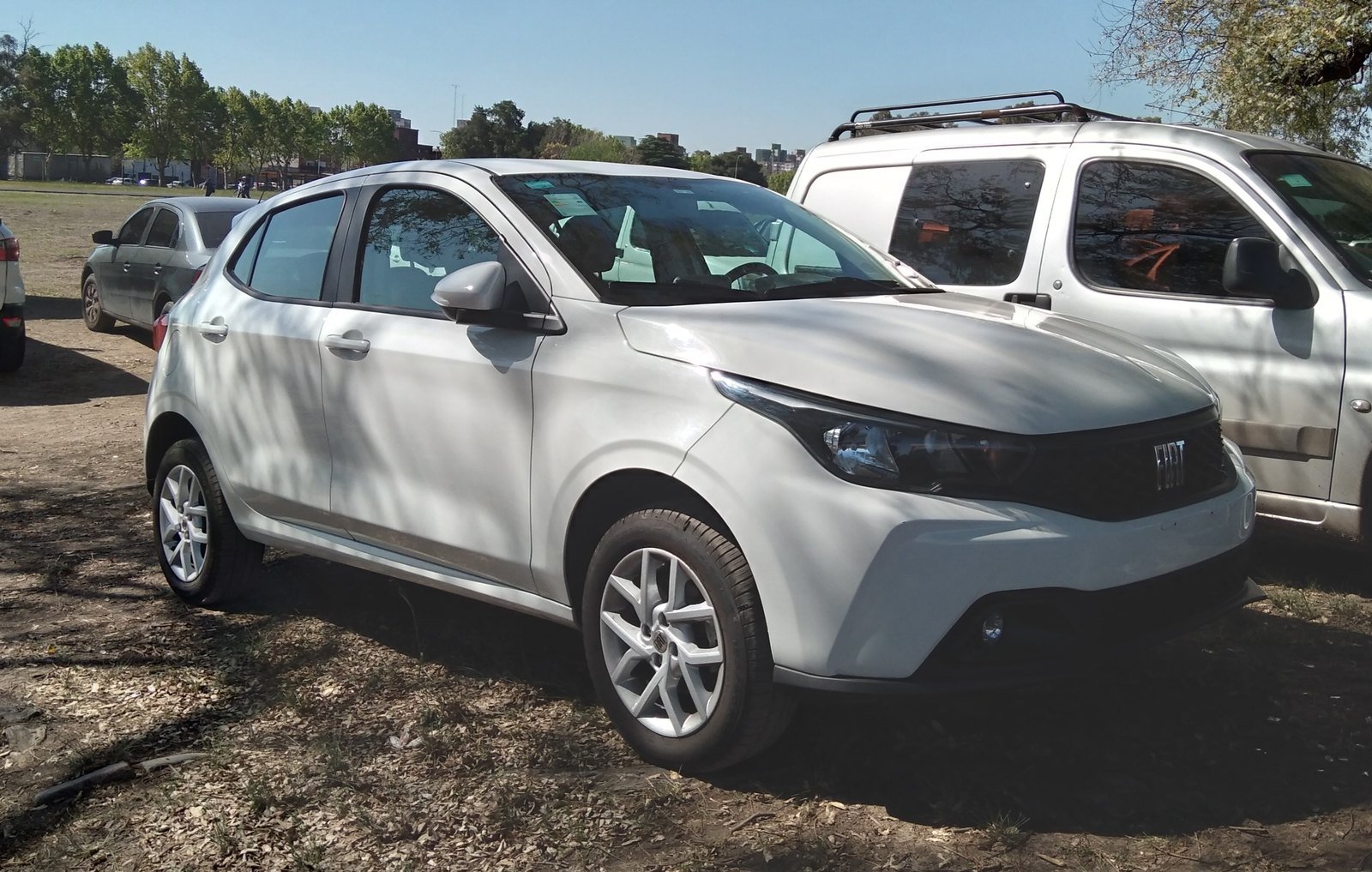 Fiat Argo branco, versão reestilizada, estacionado em um terreno de terra ao lado de uma picape