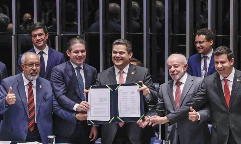Parlamentares e o presidente da República exibem o texto da Emenda Constitucional 141 no plenário do Senado