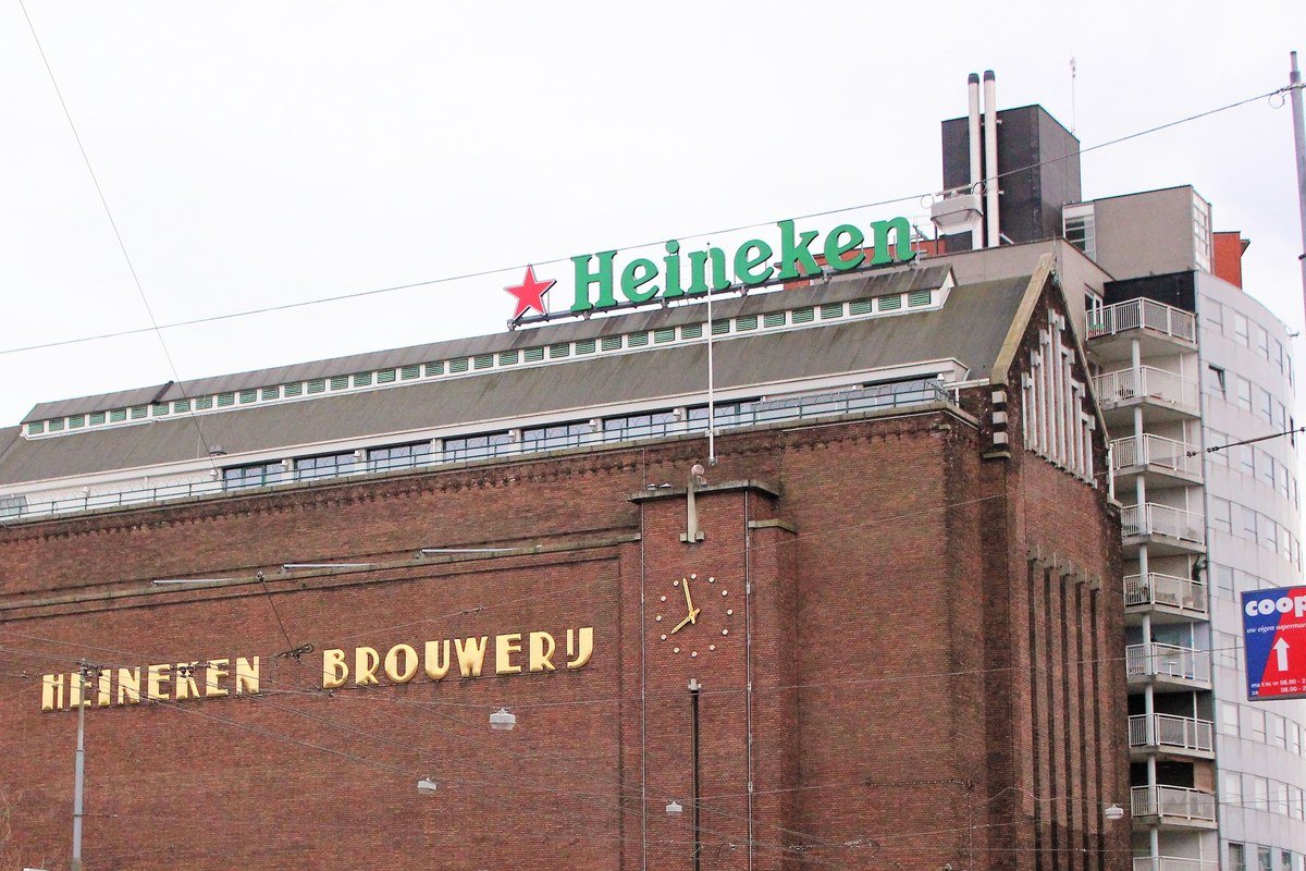 Prédio da antiga cervejaria Heineken em Amsterdã, com o logo da marca no topo e a inscrição Heineken Brouwerij na fachada