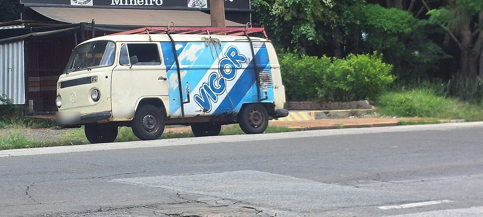 Vigor é de quem? Como a marca de laticínios de 1917 passou da JBS à mexicana Lala 3 Kombi antiga pintada de azul e branco com a palavra Vigor na lateral, estacionada em uma rua de Campinas