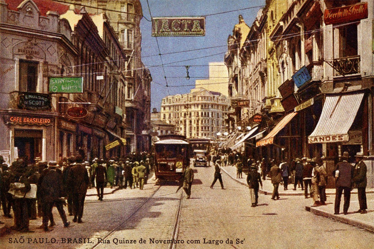 Cartão-postal colorido da Rua Quinze de Novembro, em São Paulo, com um anúncio da Lacta pendurado sobre a rua