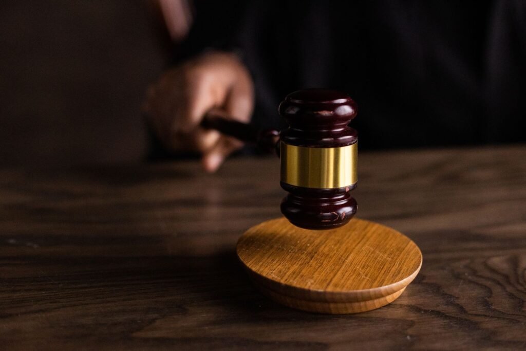 Leilão de imóveis: como funciona, riscos e custos antes de dar o lance 1 Mão batendo um martelo de leilão de madeira sobre a base