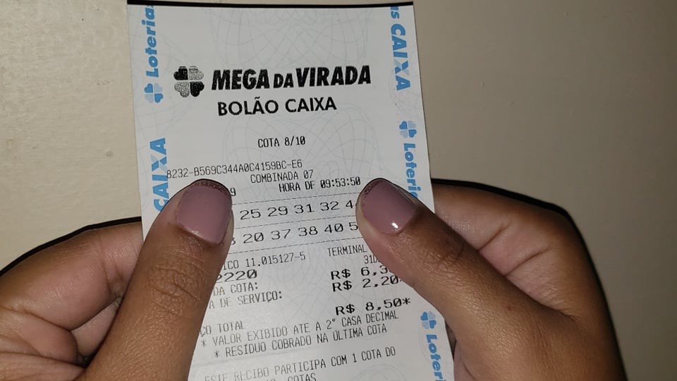 Recibo de cota de um Bolão Caixa da Mega da Virada, com a tarifa de serviço discriminada. Guarde o recibo: ele dá direito ao prêmio.