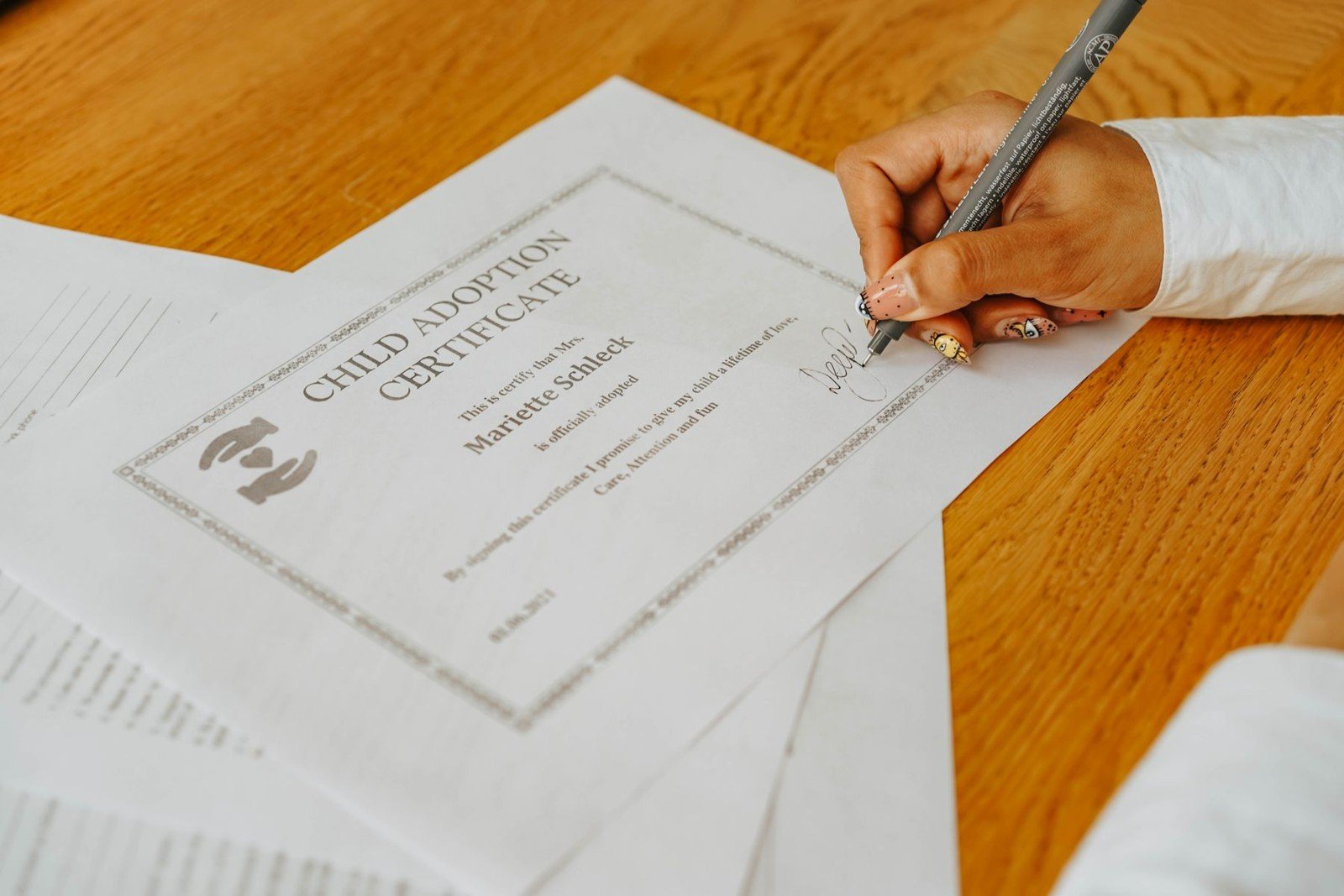 Salário-maternidade: quem tem direito, inclusive desempregadas e MEIs 7 Pessoa assina um certificado de adoção. Foto ilustrativa; o documento é estrangeiro.