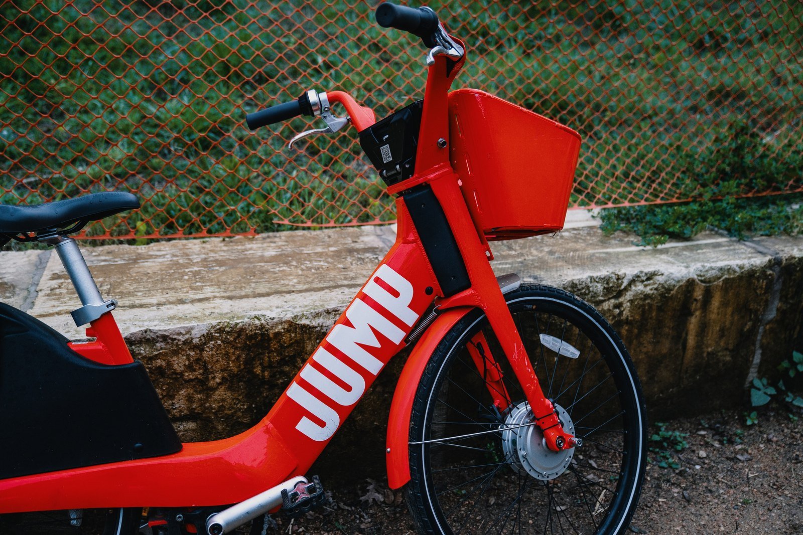 Quem é o dono da Uber? A história da empresa americana e as curiosidades do app no Brasil e no mundo 5 Bicicleta elétrica vermelha da JUMP, com cesto na frente, estacionada perto de uma cerca em Austin