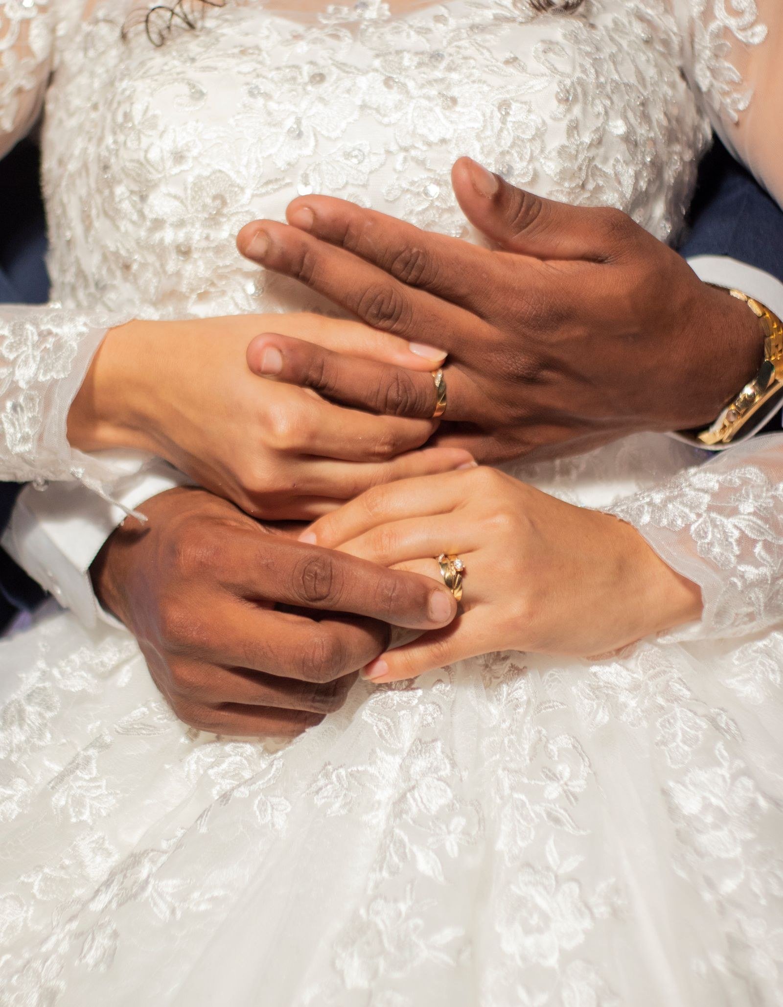 União estável ou casamento: diferenças nos bens, na herança e na pensão 5 Mãos de um casal de noivos com alianças sobre o vestido de noiva