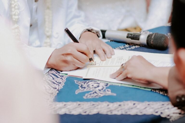 Mão de um noivo assinando o documento do casamento sobre uma mesa