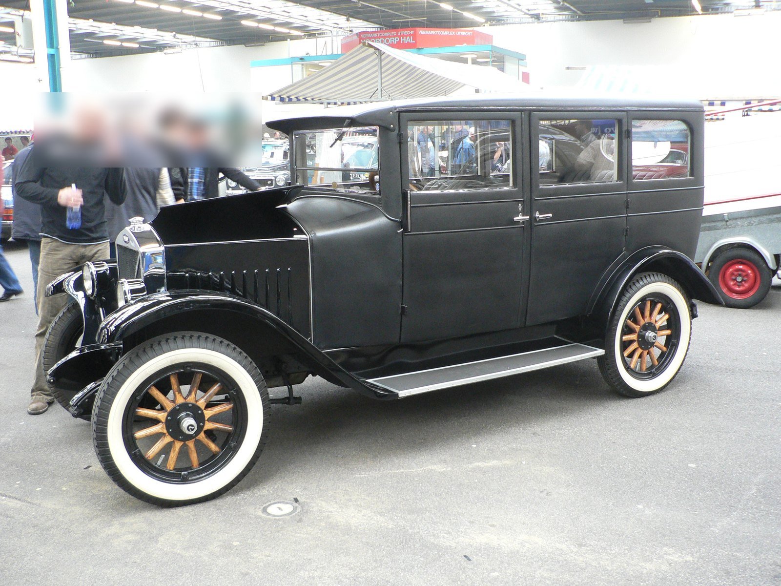 Volvo ÖV4 preto de 1927, conhecido como Jakob, com rodas de raios de madeira e pneus de faixa branca, exposto em um salão